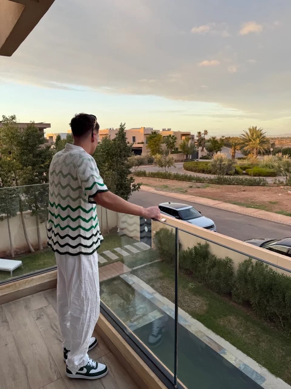 Une personne sur un balcon avec vue sur un quartier bordé de palmiers